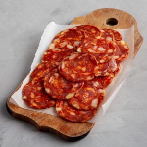 Spanish chorizo salami sausage on a rustic wooden board on a gray background, side view.